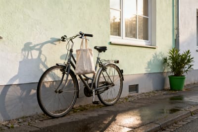 Alltagsfahrrad lehnt im Morgenlicht an einer hell verputzten Hauswand